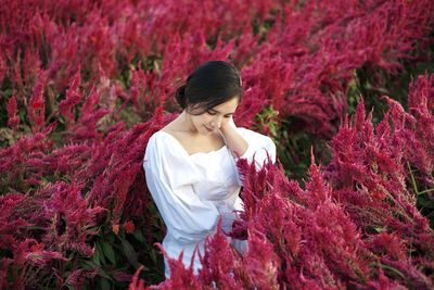 Full length of woman standing by red flowering plants