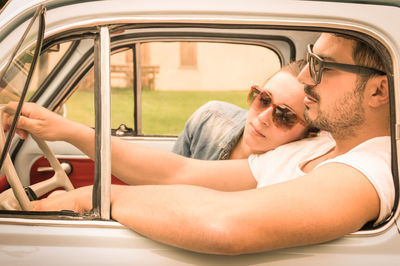 Couple traveling in car seen through vintage car