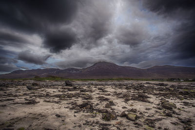 Scenic view of landscape and mountains against storm clouds