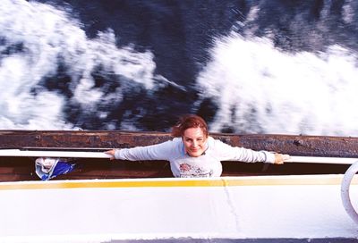 High angle portrait of woman standing by railing in ship