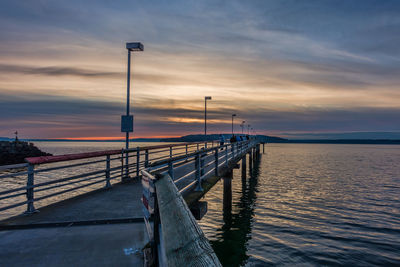 Pier over sea against sky during sunset