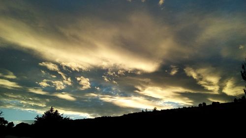 Low angle view of silhouette trees against dramatic sky