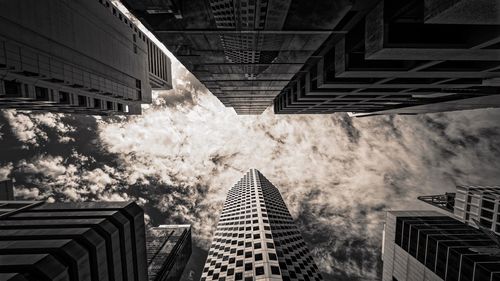 Low angle view of buildings against cloudy sky in city