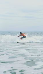 Mid adult man surfing on sea against sky