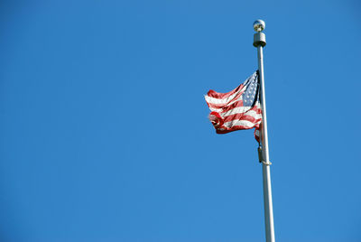 Low angle view of flags flag against clear blue sky