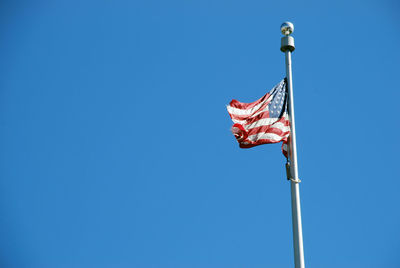 Low angle view of american flag against clear blue sky