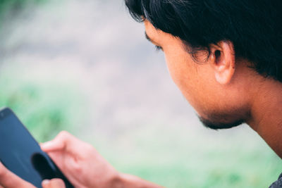 Close-up of young man using mobile phone outdoors