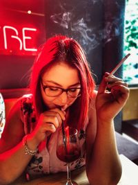 Portrait of a young woman drinking glass at restaurant