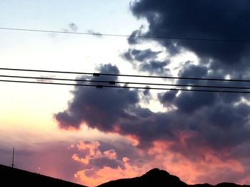 Low angle view of silhouette electricity pylon against sky