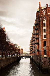 Buildings by river against sky