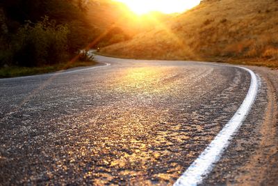 Road by street against sky during sunset