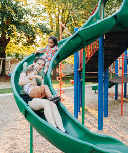 Young millennial mother and diverse mixed race toddler boy at park on nice summer day having fun