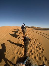 View of man riding on sand at desert against clear sky