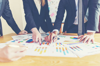 Business colleagues with colorful graphs at desk in office
