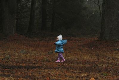 Side view of baby girl walking on grassy field during autumn