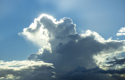 Low angle view of sunlight streaming through clouds