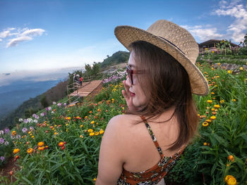 Beautiful young woman wearing hat on land against sky