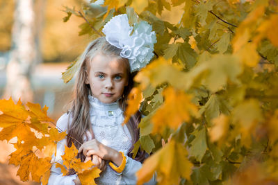 Portrait of cute girl standing by plants during autumn