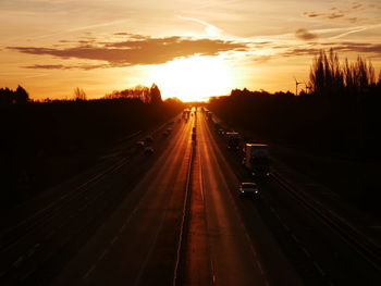 Vehicles on road against sky during sunrise