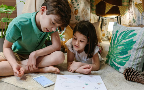 Brothers playing treasure hunting game in a diy tent at home