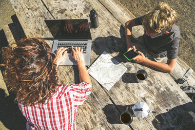 Mother and son using technology in forest during sunny day