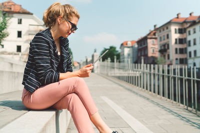 Portrait of young woman sitting on street