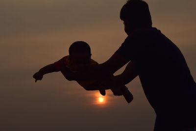 Silhouette man against orange sky during sunset