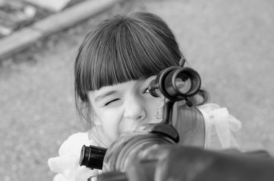 Close-up of girl playing with telescope outdoors