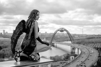 Woman wearing costume while sitting kneeling sky in city