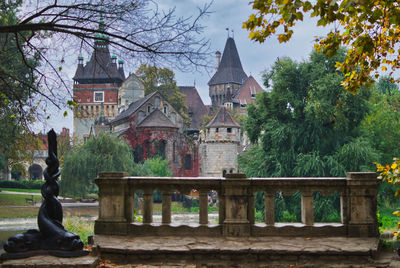 Statue by historic building against trees