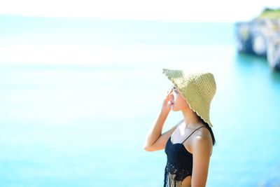 Midsection of woman wearing hat against sea