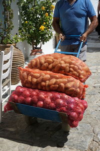 Midsection of man pulling cart stacked with sacks