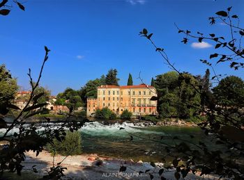 Scenic view of lake and buildings against blue sky