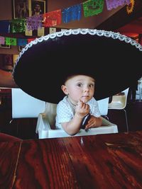Portrait of cute baby boy wearing hat while sitting on high chair