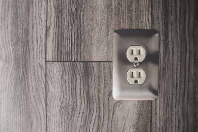 Close-up view of an electrical power outlet on a wooden door. 