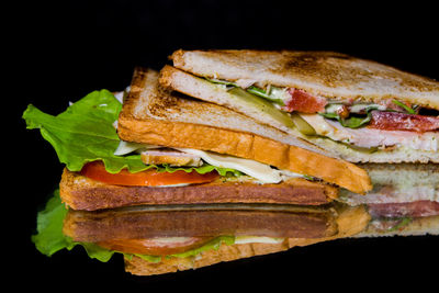 Close-up of sandwich and bread against black background