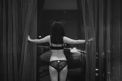 Rear view of woman standing against curtain