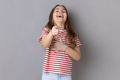 Portrait of young woman standing against gray background