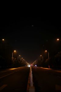 Illuminated street lights against sky in city at night