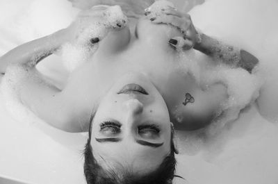 High angle view of seductive woman holding breast in bathtub