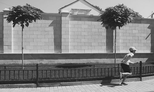 Side view of man by swimming pool against building