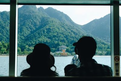 Rear view of silhouette woman looking through window