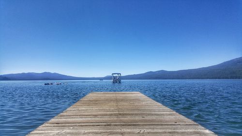 Pier over lake against blue sky