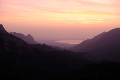 Scenic view of silhouette mountains against orange sky