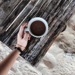 High angle view of hand holding coffee cup