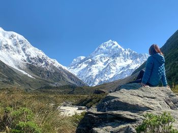 Rear view of person on snowcapped mountains against clear blue sky