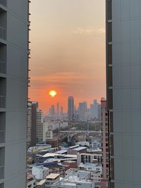 Modern buildings in city against sky during sunset