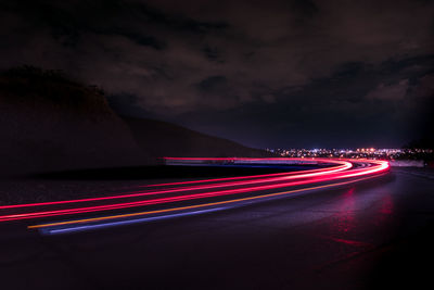 Light trails on road against sky at night