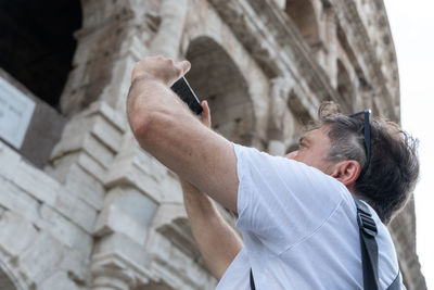 Low angle view of man using mobile phone outdoors