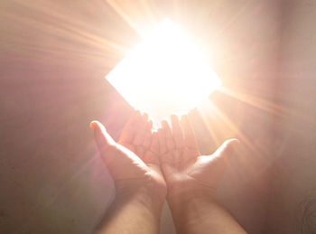 Close-up of praying hand holding illuminated light